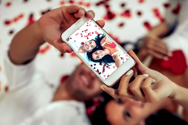 A couple lying on a bed taking a selfie